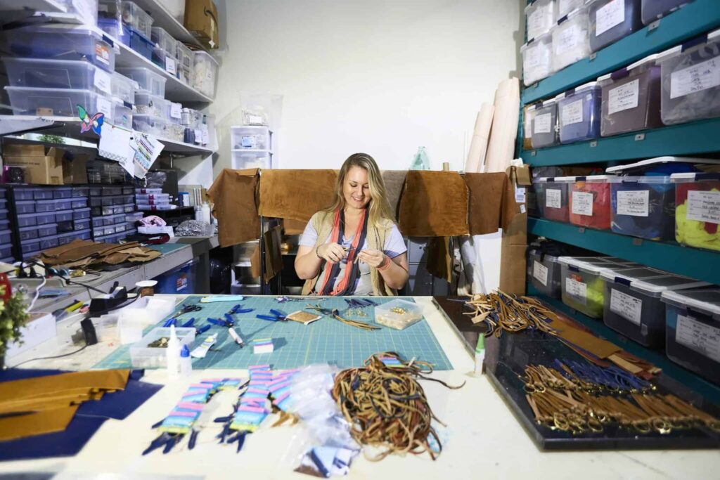 A human trafficking survivor making jewelry in a nice office