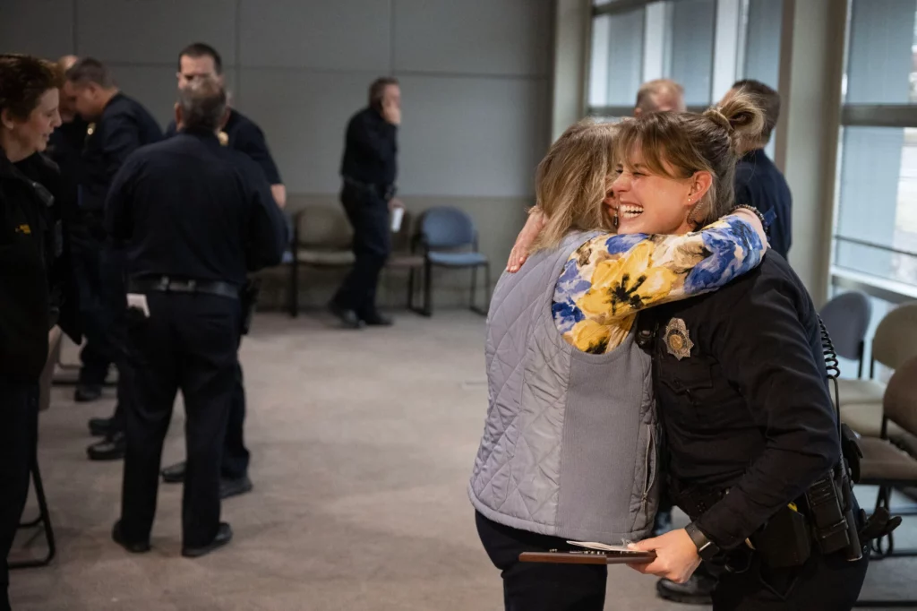 Woman hugging a female police officer. The officer is holding an award