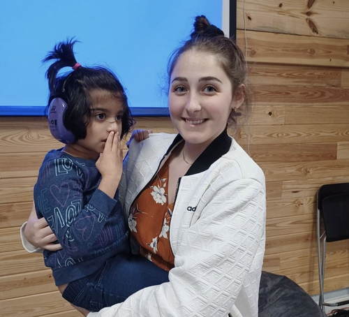 A doctor holding a little girls that has headphones on