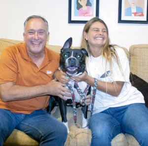 Happy couple with therapy dog for emotional support and recovery.