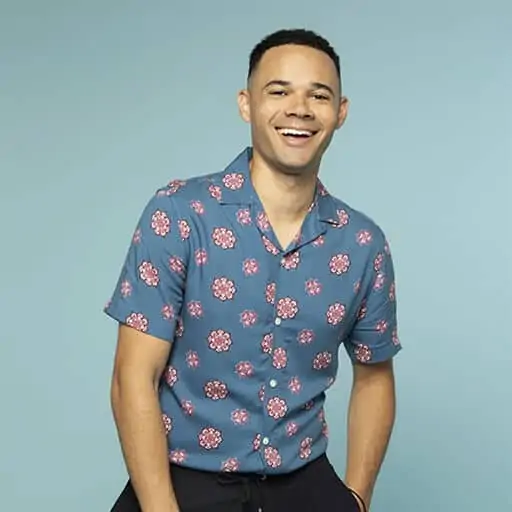 Vibrant man smiling in casual floral shirt, representing trust and positivity for The Promise initiative.
