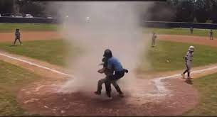 Umpire picking up a kid that was in a dust devil