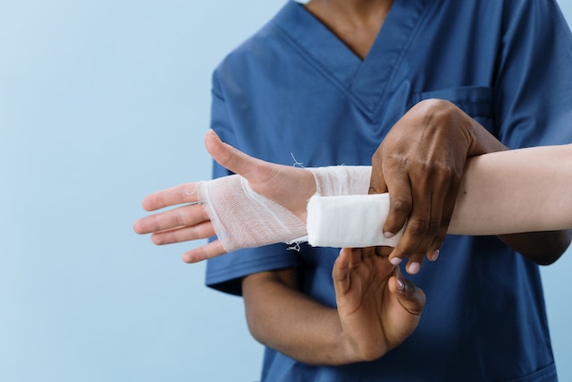 A doctor wrapping up a patients arm with bandages