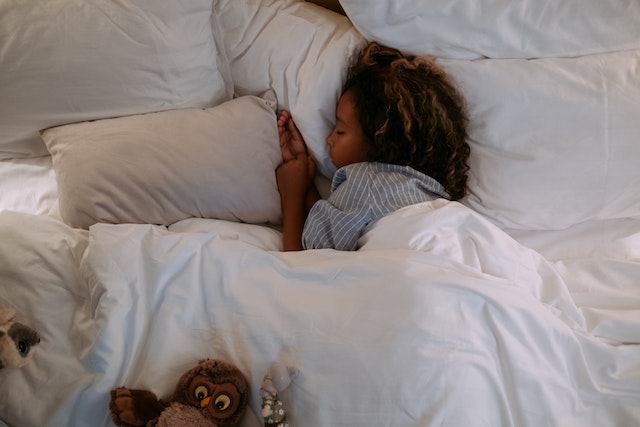 Kid sleeping on their side in a bed