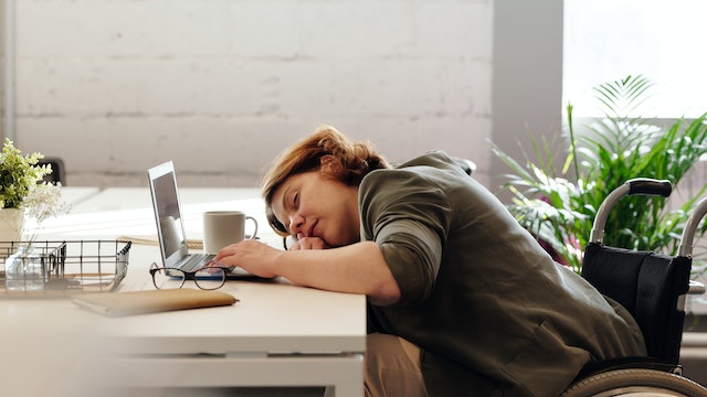 A lady that fell asleep at her desk with her computer out.