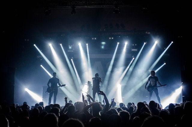 silhouette of band members on stage at large concert venue