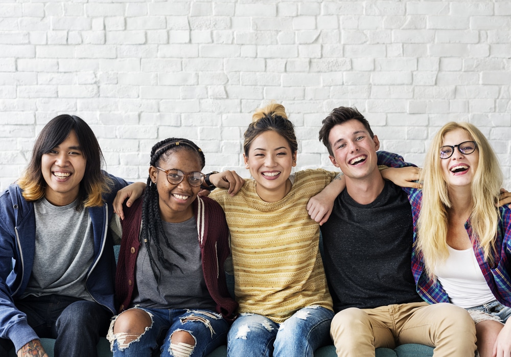 A group of friends in their mid 20's sitting on a couch.