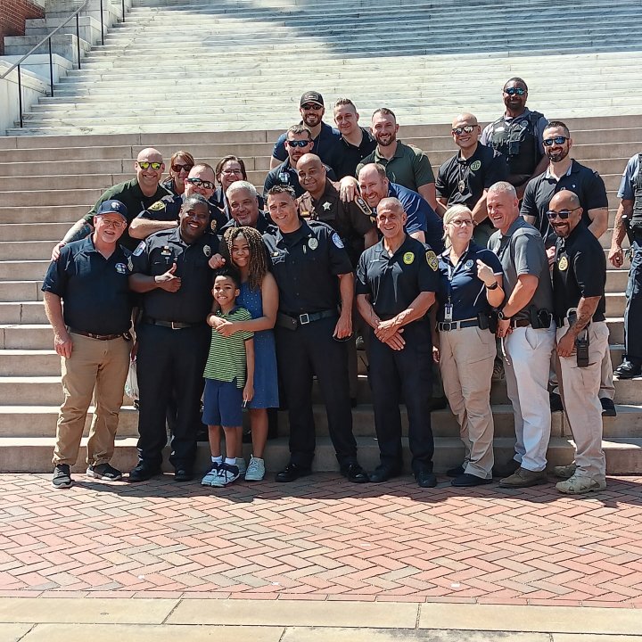 A group of police offers and a 13 year old girl in the middle of the picture laughing with them